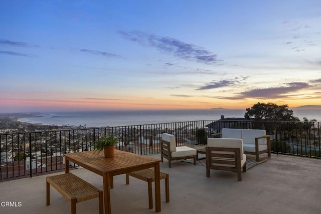 patio terrace at dusk featuring outdoor lounge area and a water view