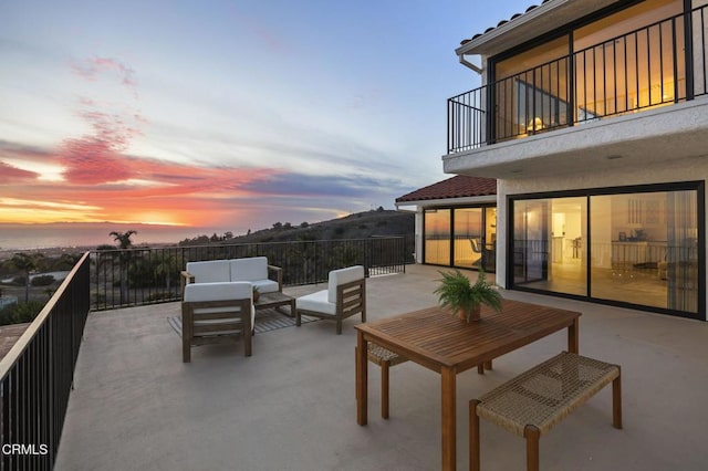 patio terrace at dusk featuring an outdoor hangout area and a balcony