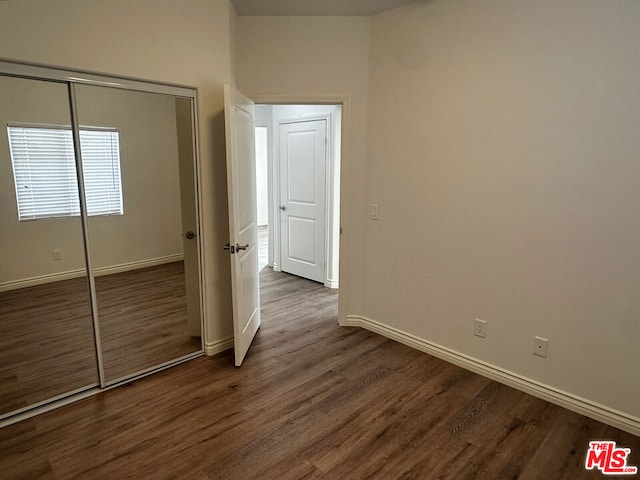 unfurnished bedroom featuring a closet and dark wood-type flooring