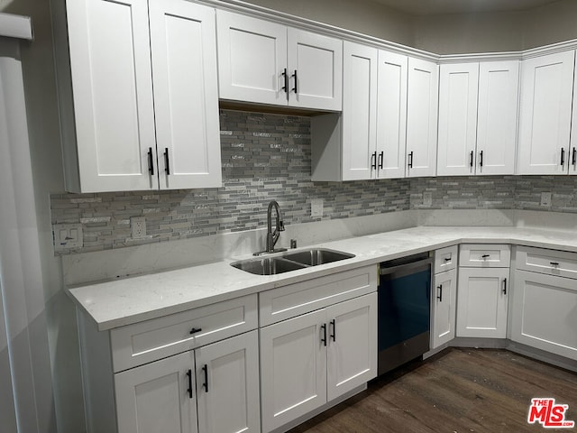 kitchen with light stone counters, stainless steel dishwasher, dark wood-type flooring, sink, and white cabinetry