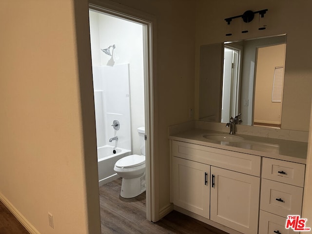 full bathroom featuring hardwood / wood-style floors, vanity, toilet, and shower / washtub combination