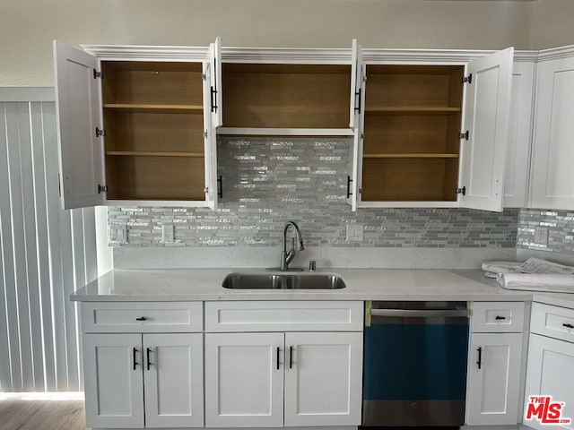 kitchen featuring dishwasher, white cabinetry, light stone countertops, and sink