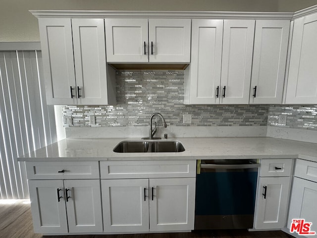 kitchen with dishwasher, light stone counters, white cabinetry, and sink