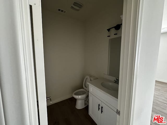 bathroom with vanity, toilet, and wood-type flooring