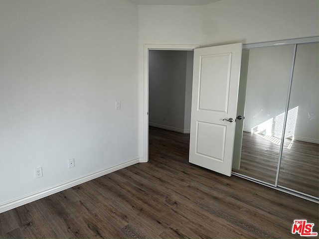 unfurnished bedroom featuring dark hardwood / wood-style floors and a closet