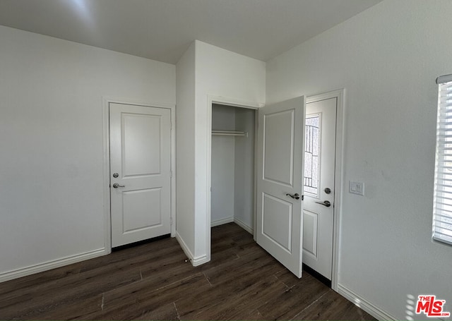 unfurnished bedroom featuring a closet and dark wood-type flooring