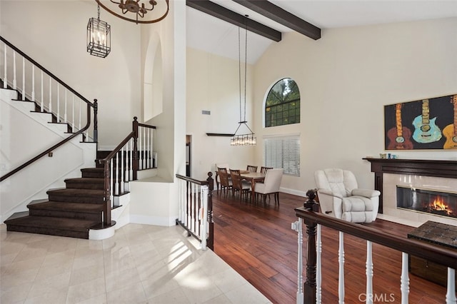 stairway with a tiled fireplace, tile patterned flooring, high vaulted ceiling, and beamed ceiling