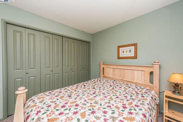 bedroom with a textured ceiling, carpet floors, and a closet