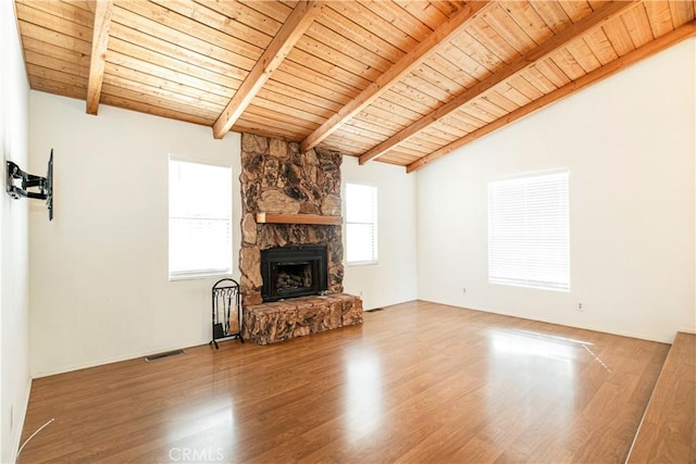 unfurnished living room featuring hardwood / wood-style flooring, lofted ceiling with beams, a stone fireplace, and wood ceiling