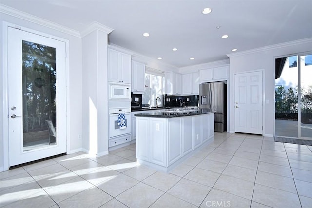 kitchen featuring white cabinetry, a center island, light tile patterned floors, and white appliances