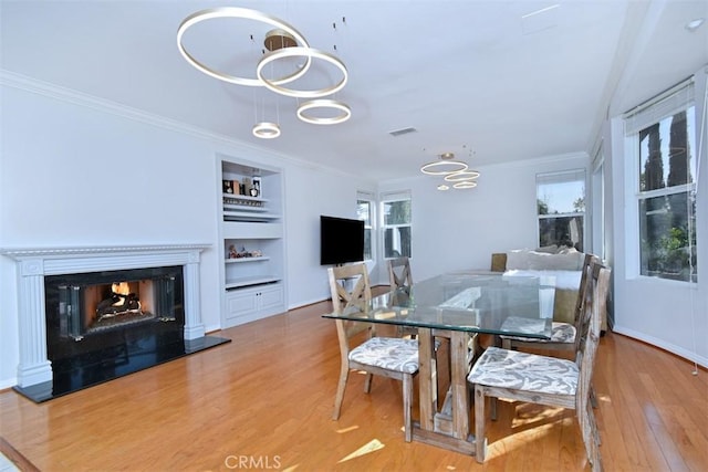 dining space featuring hardwood / wood-style floors, built in shelves, and crown molding