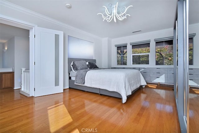 bedroom with hardwood / wood-style floors, an inviting chandelier, and ornamental molding