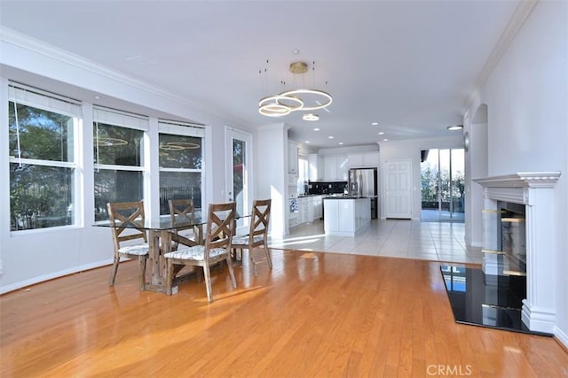 dining space with an inviting chandelier, light hardwood / wood-style flooring, and crown molding