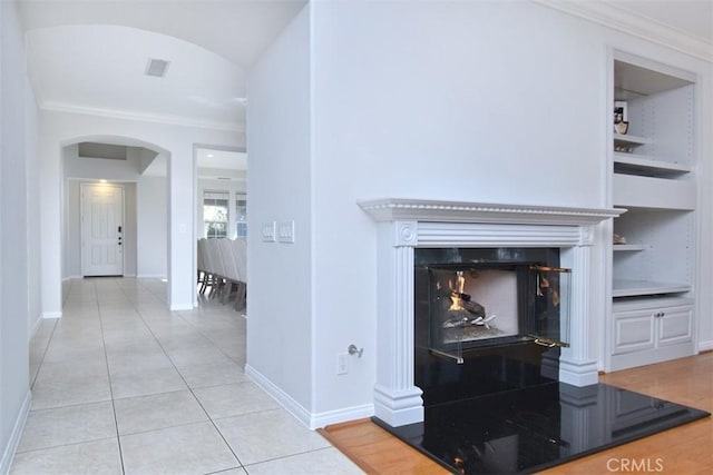 hallway featuring built in shelves, crown molding, and light tile patterned flooring