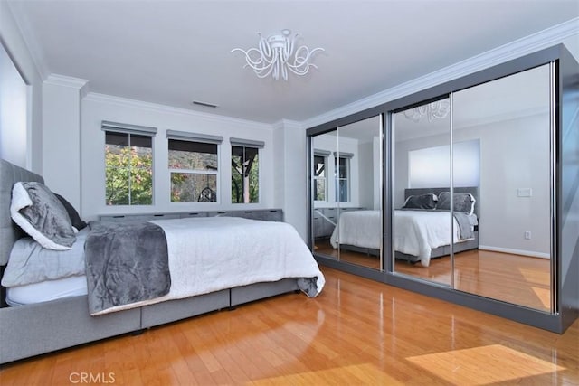 bedroom with hardwood / wood-style floors, ornamental molding, and a chandelier