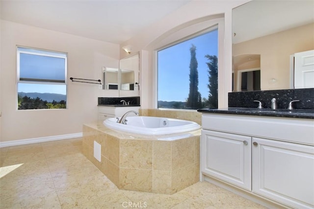 bathroom featuring plenty of natural light, vanity, and a relaxing tiled tub