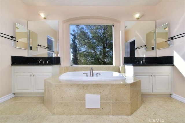 bathroom featuring vanity, a relaxing tiled tub, and tile patterned floors