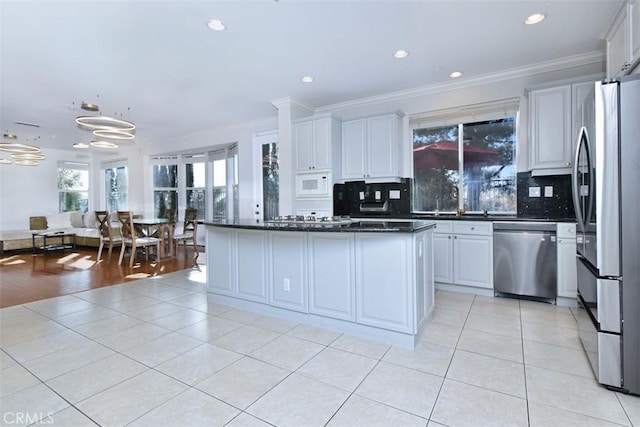 kitchen featuring appliances with stainless steel finishes, tasteful backsplash, light hardwood / wood-style flooring, and ornamental molding