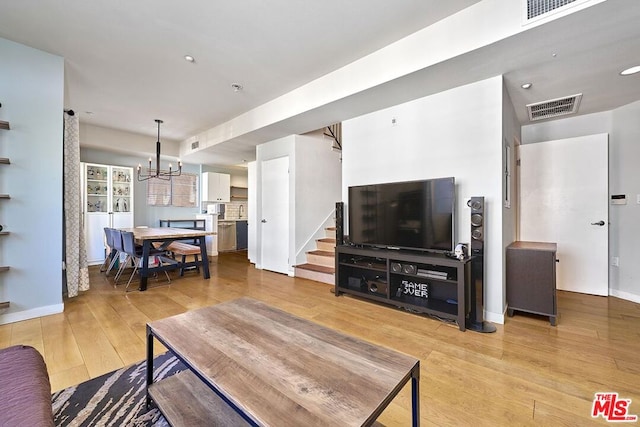 living room with light hardwood / wood-style floors and a notable chandelier