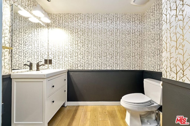 bathroom featuring hardwood / wood-style floors, vanity, toilet, and an inviting chandelier