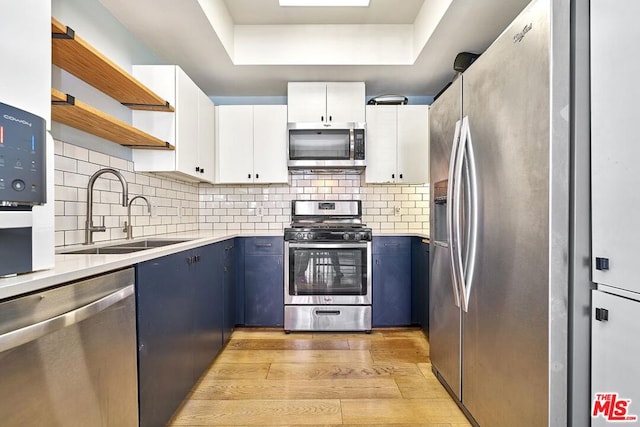 kitchen featuring stainless steel appliances, blue cabinets, sink, light hardwood / wood-style flooring, and white cabinets