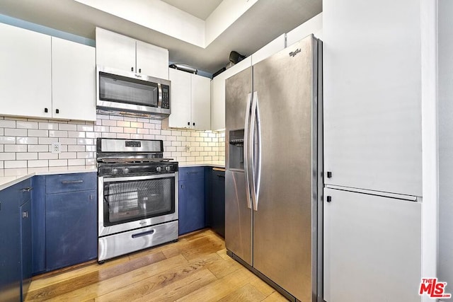 kitchen featuring white cabinets, stainless steel appliances, blue cabinetry, and light hardwood / wood-style floors