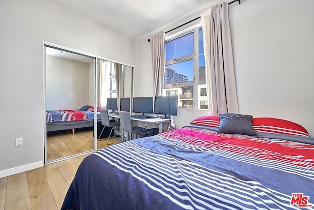 bedroom featuring multiple windows, light hardwood / wood-style floors, and a closet