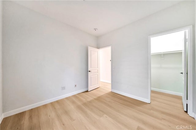 unfurnished bedroom featuring a walk in closet, light wood-type flooring, and a closet