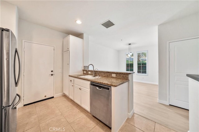 kitchen with white cabinets, sink, appliances with stainless steel finishes, decorative light fixtures, and kitchen peninsula