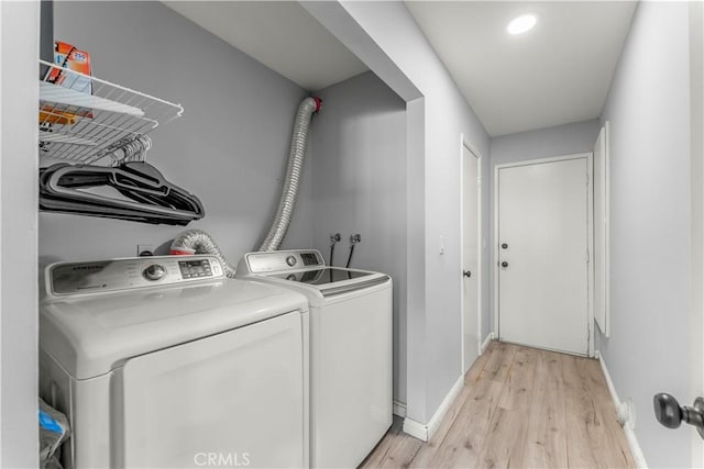 clothes washing area with washer and clothes dryer and light hardwood / wood-style flooring