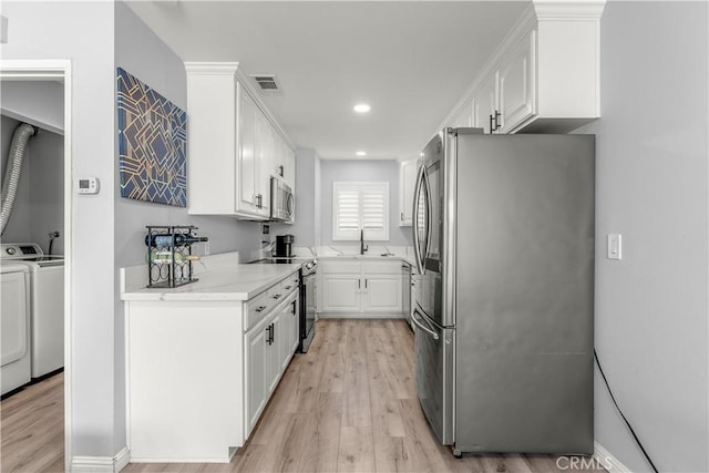 kitchen featuring washer and clothes dryer, sink, white cabinetry, and appliances with stainless steel finishes