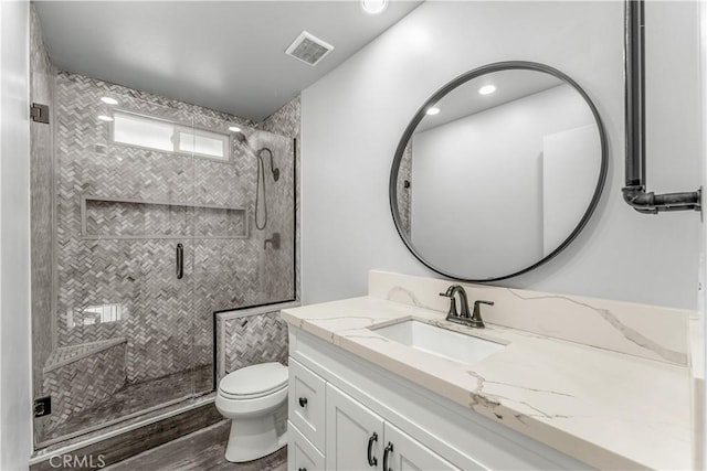 bathroom with hardwood / wood-style flooring, an enclosed shower, vanity, and toilet