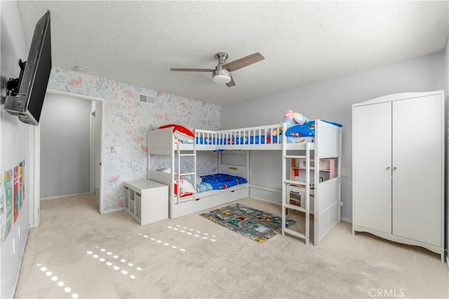 bedroom featuring light carpet, ceiling fan, and a textured ceiling