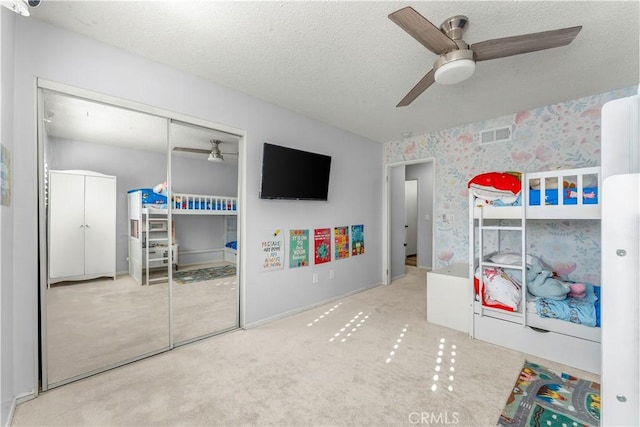 unfurnished bedroom with ceiling fan, carpet, a closet, and a textured ceiling