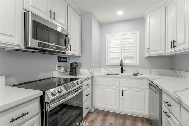 kitchen with sink, stainless steel appliances, white cabinetry, and light stone countertops