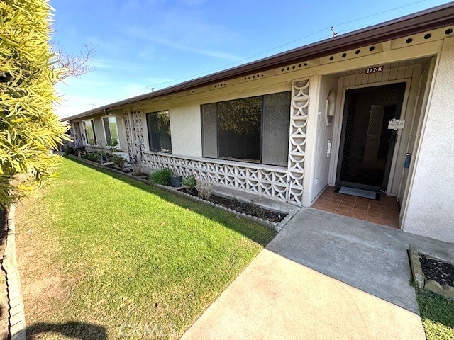 entrance to property with a yard and stucco siding