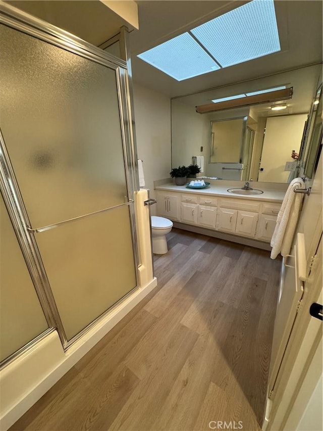 full bathroom with a stall shower, vanity, toilet, and wood finished floors