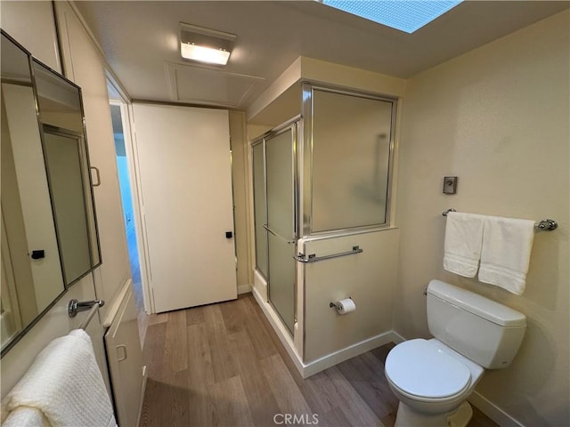 bathroom with baseboards, wood finished floors, toilet, and a shower stall