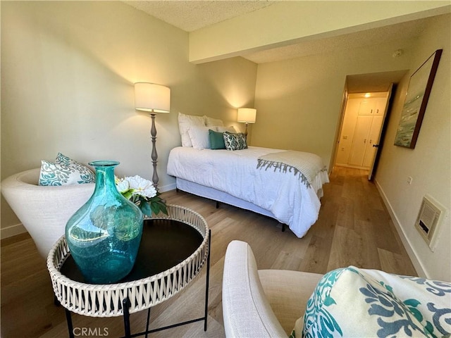 bedroom featuring a textured ceiling, wood finished floors, visible vents, and baseboards