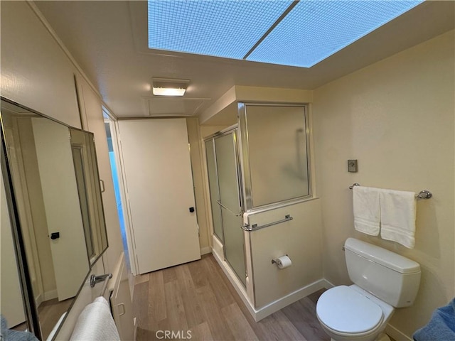 bathroom with toilet, a stall shower, baseboards, and wood finished floors