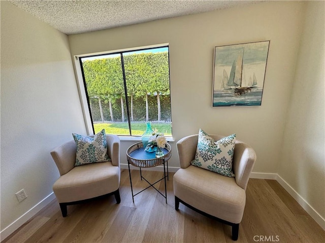 sitting room featuring plenty of natural light, baseboards, and wood finished floors