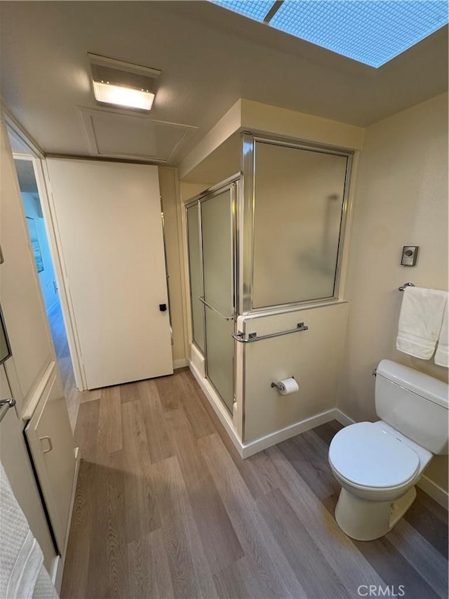 full bathroom with toilet, a stall shower, baseboards, and wood finished floors