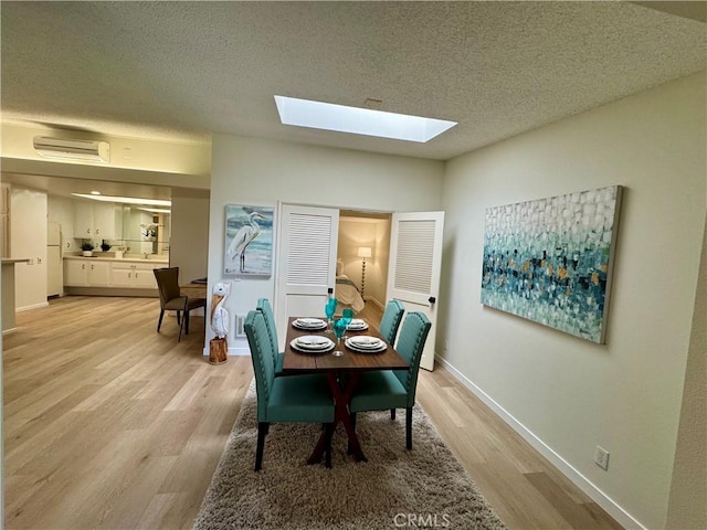 dining area with light wood-style floors, a wall unit AC, a textured ceiling, and baseboards