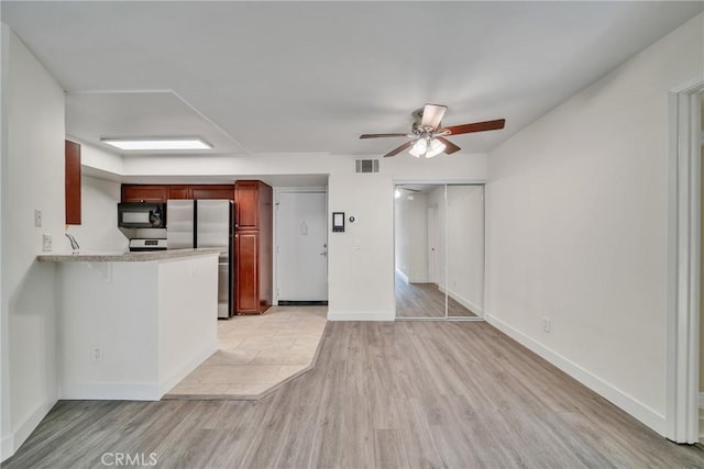 kitchen with stainless steel refrigerator, ceiling fan, kitchen peninsula, and light wood-type flooring