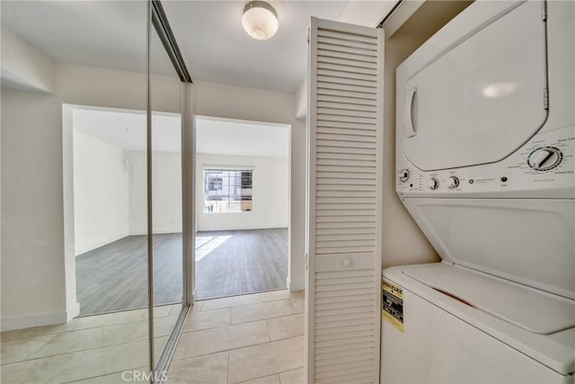 laundry room with light hardwood / wood-style flooring and stacked washing maching and dryer