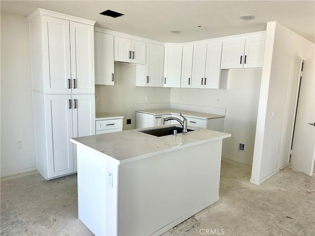 kitchen with sink, an island with sink, and white cabinets