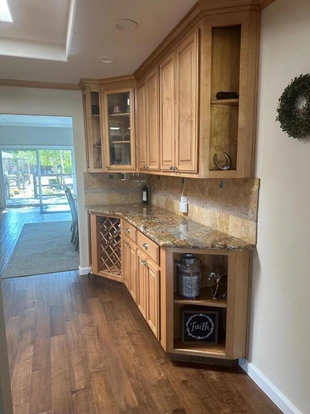 bar featuring dark hardwood / wood-style flooring, backsplash, and light stone countertops