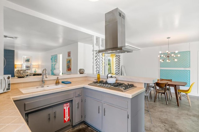 kitchen featuring stainless steel gas stovetop, sink, a kitchen bar, kitchen peninsula, and island exhaust hood