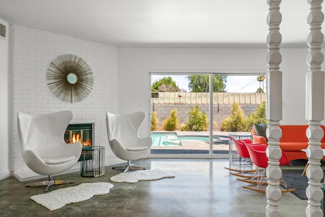 living area featuring concrete floors and a brick fireplace