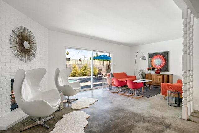 living area with concrete flooring and brick wall